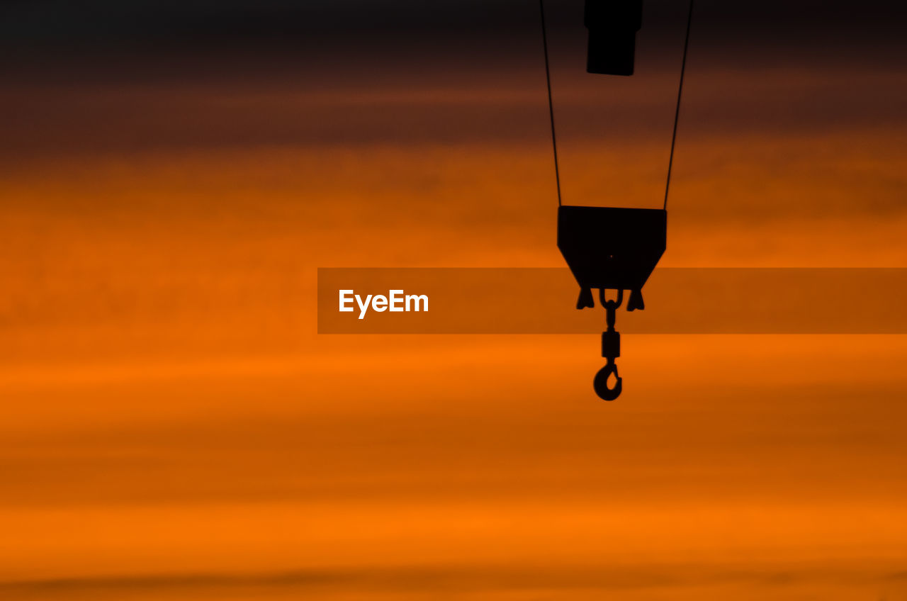 Silhouette hook hanging against sky during sunset