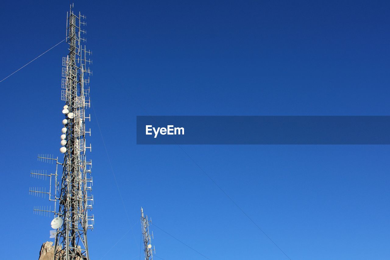 Low angle view of communications tower against blue sky