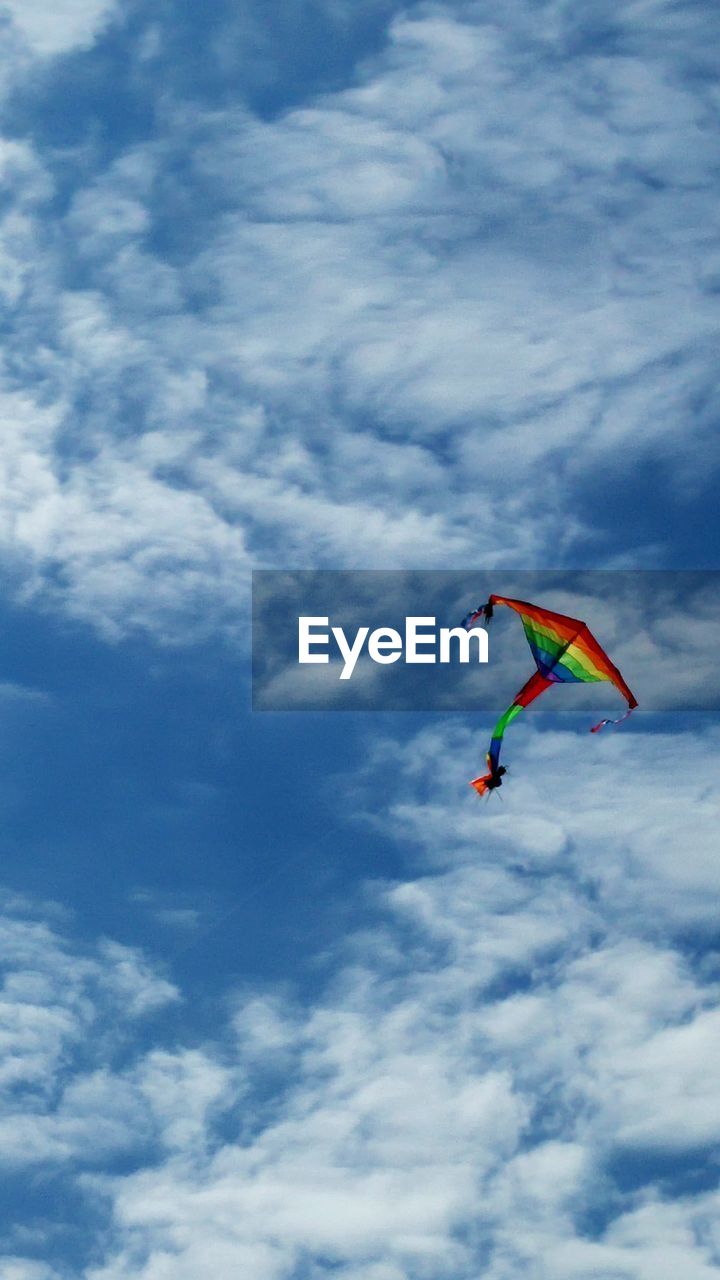 Low angle view of colorful kite flying against cloudy sky