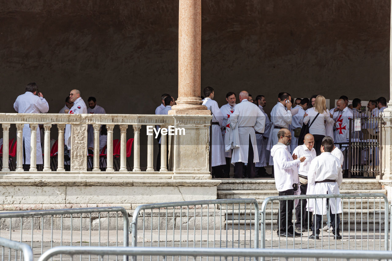 SIDE VIEW OF PEOPLE STANDING AGAINST THE RAILING