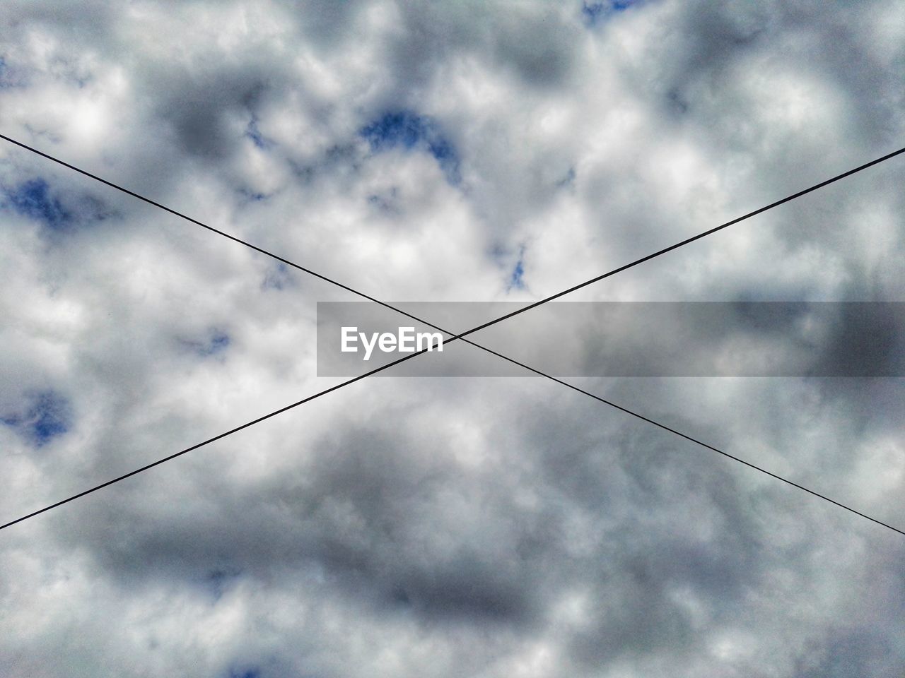 Low angle view of cables against cloudy sky