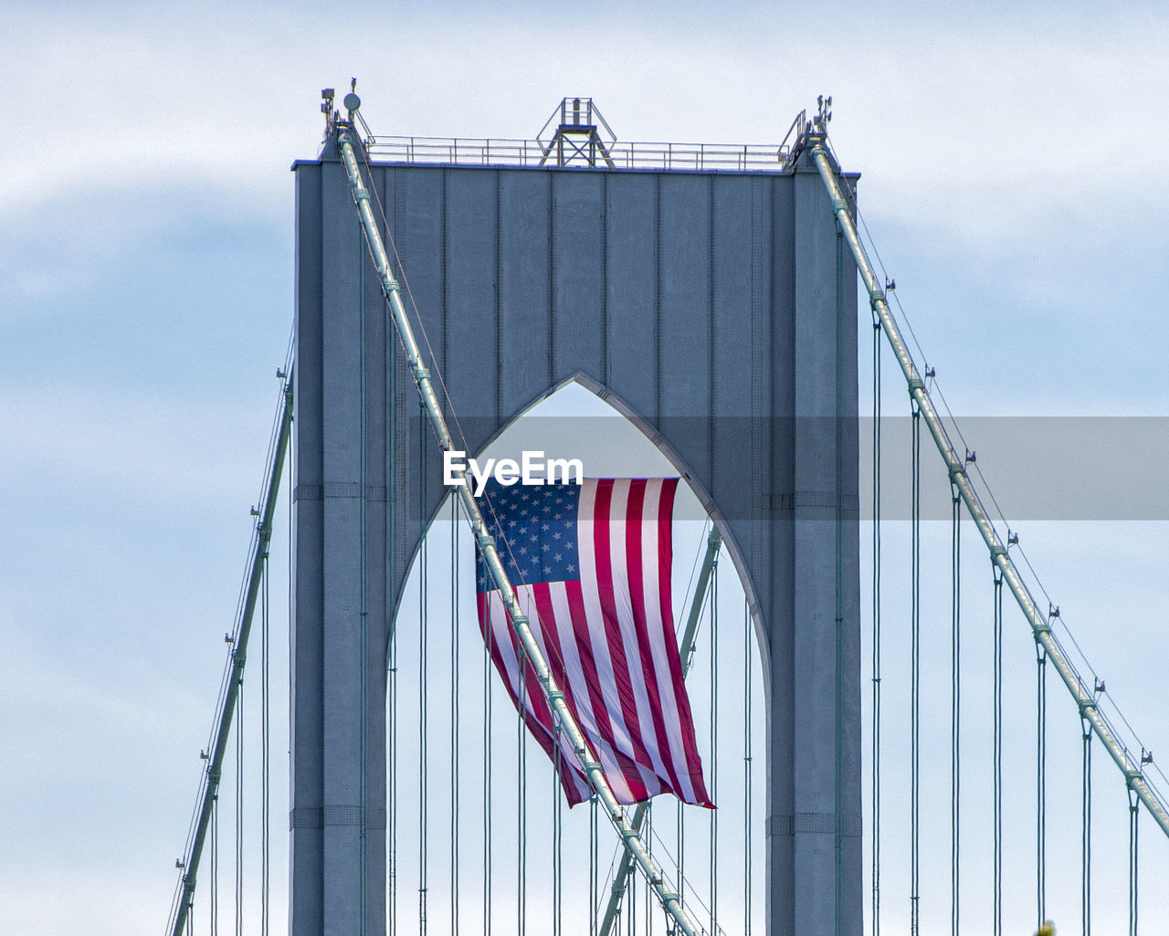 LOW ANGLE VIEW OF FLAGS ON BRIDGE AGAINST SKY