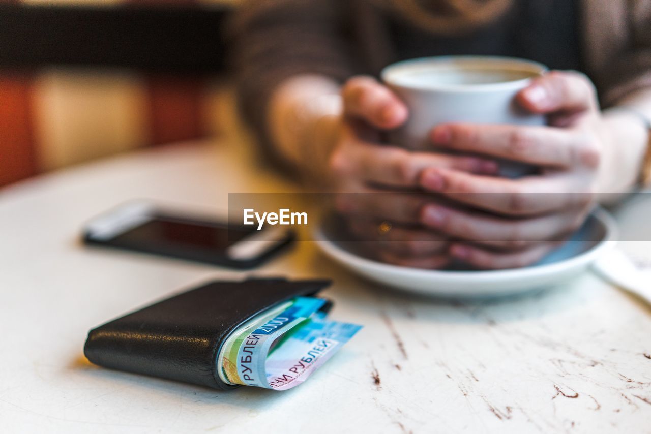 Cropped hands of woman holding coffee cup at cafe