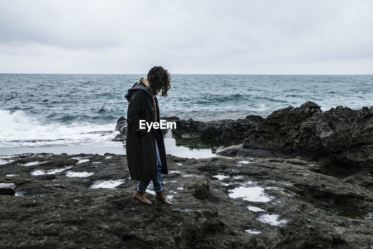 Full length of woman standing on beach against sky