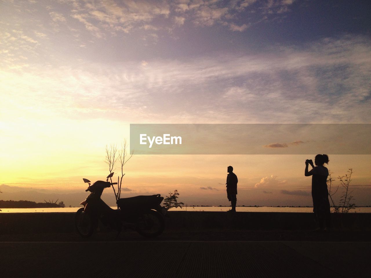 Silhouette of person taking photographs at sunset