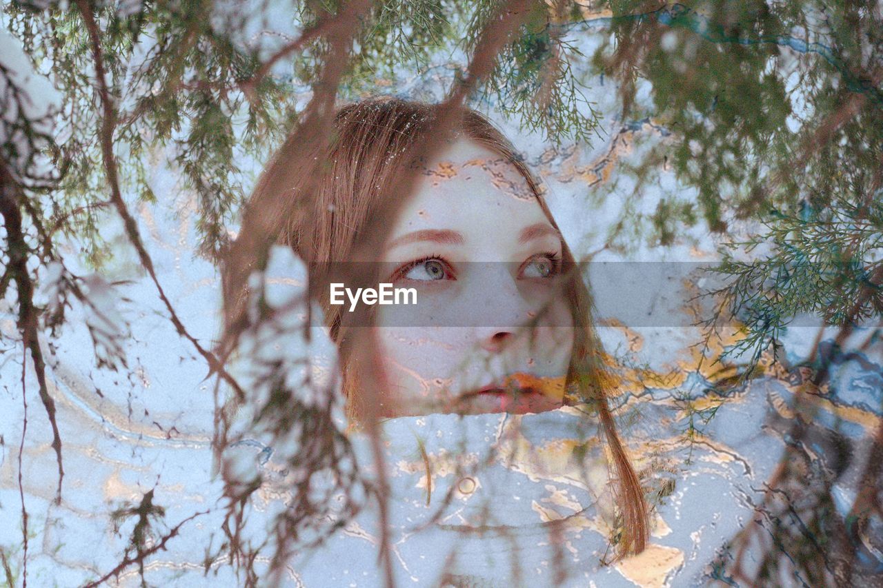 PORTRAIT OF GIRL IN TREE AGAINST PLANTS