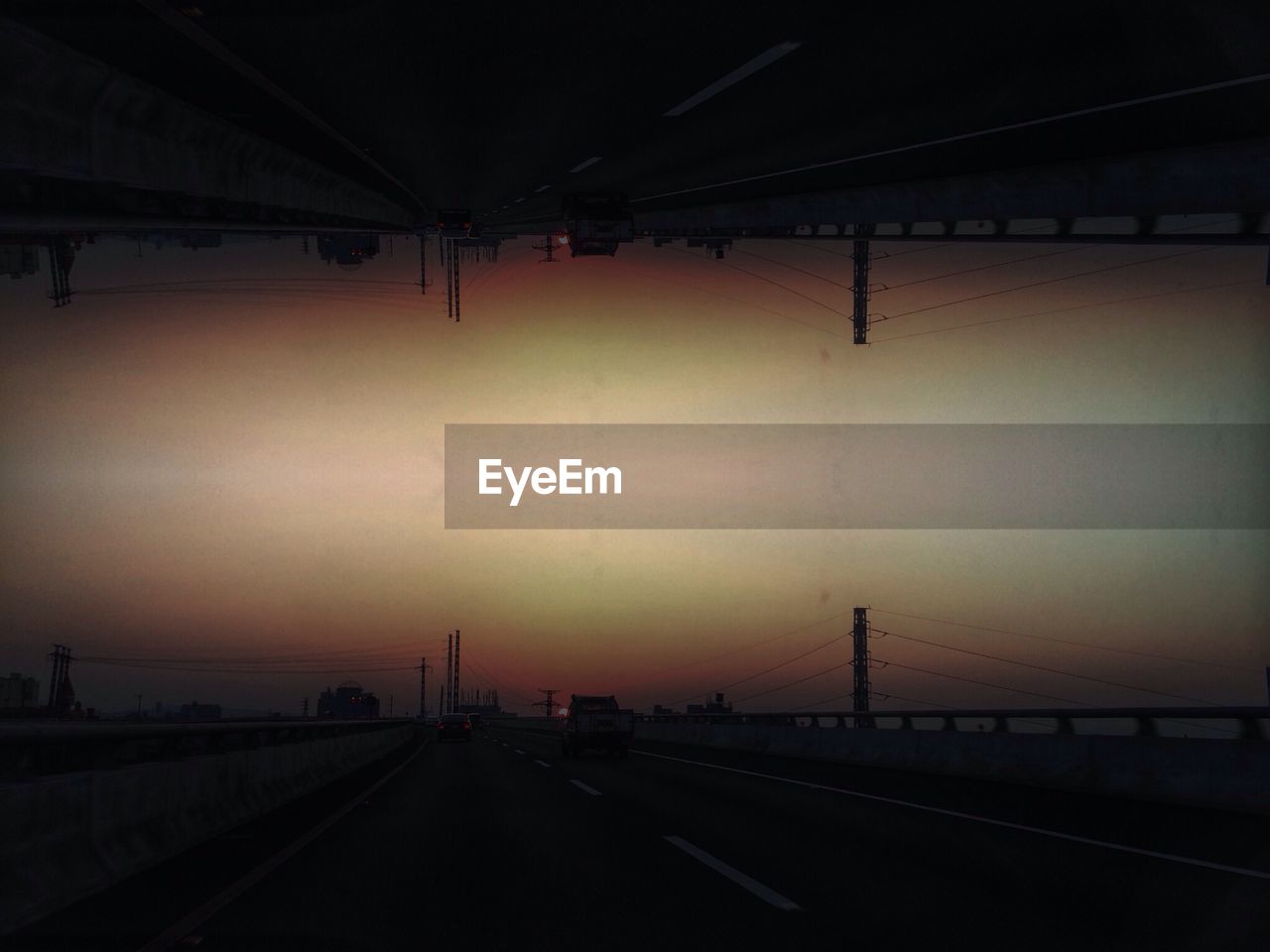 EMPTY ROAD WITH BRIDGE IN BACKGROUND AT SUNSET