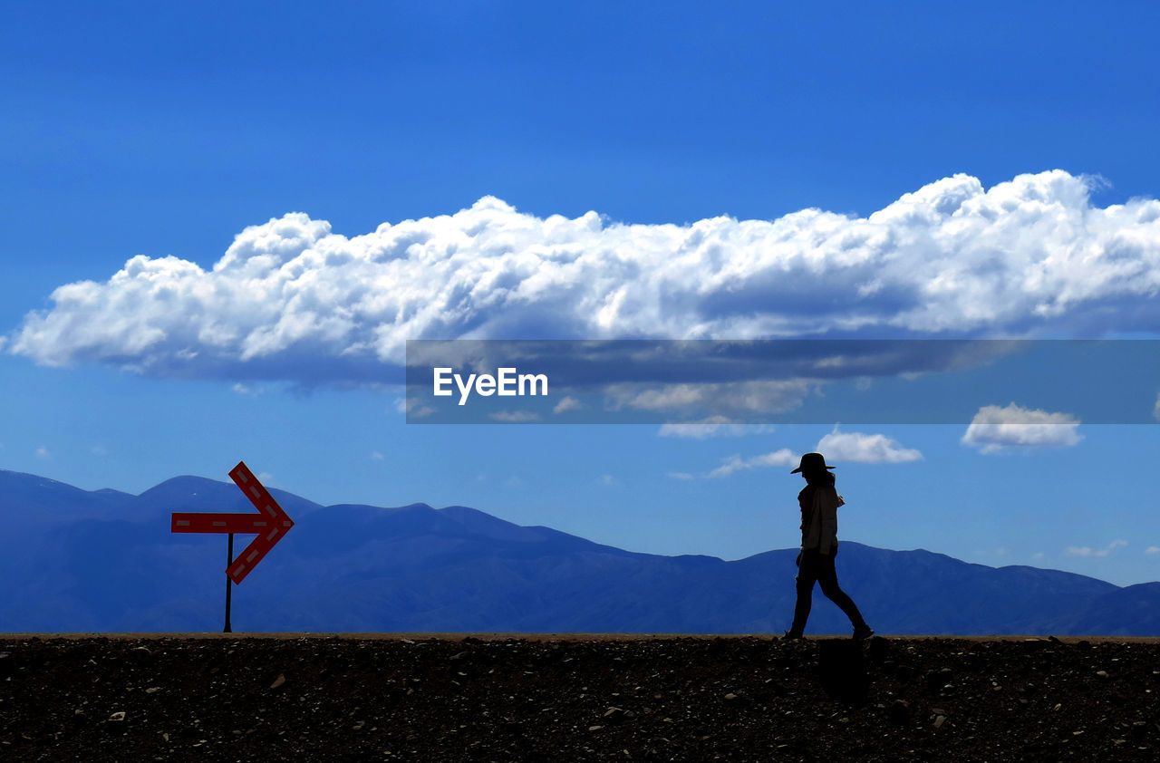 Silhouette woman walking on field against mountain ranges