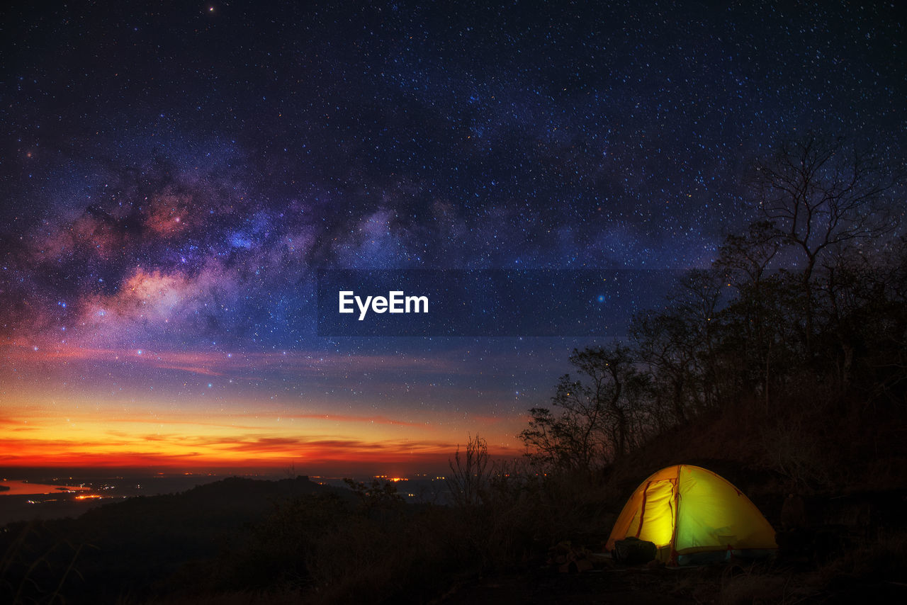 Illuminated tent on field against star field at night