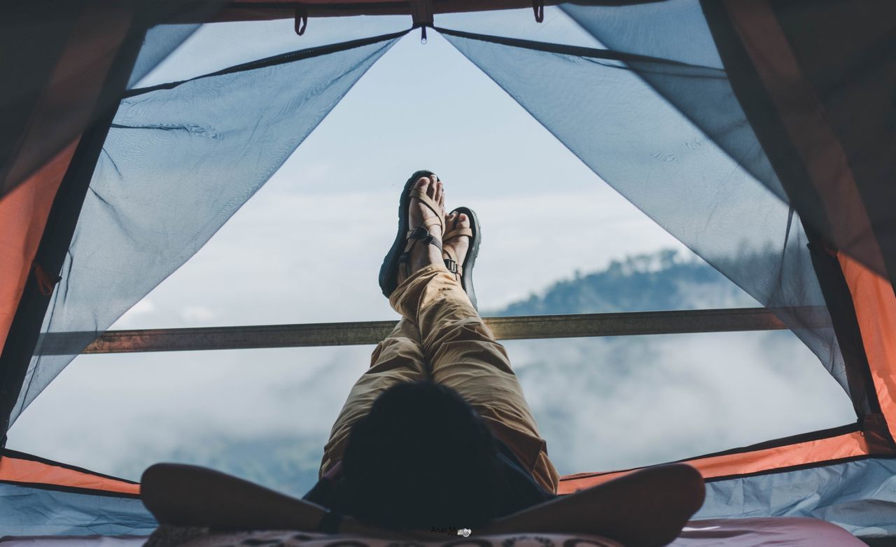 Man lying in tent with mountains in background