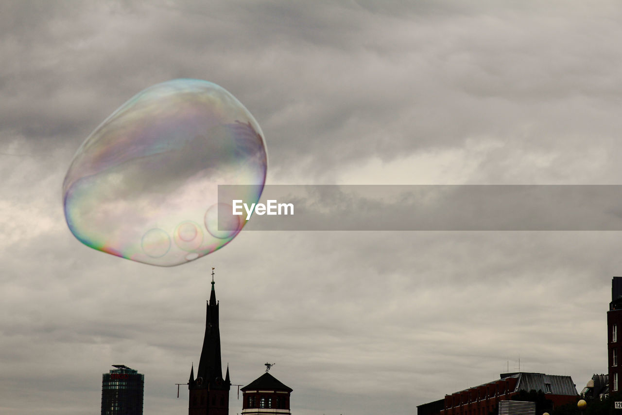 LOW ANGLE VIEW OF BUBBLES AGAINST BUILDINGS IN CITY