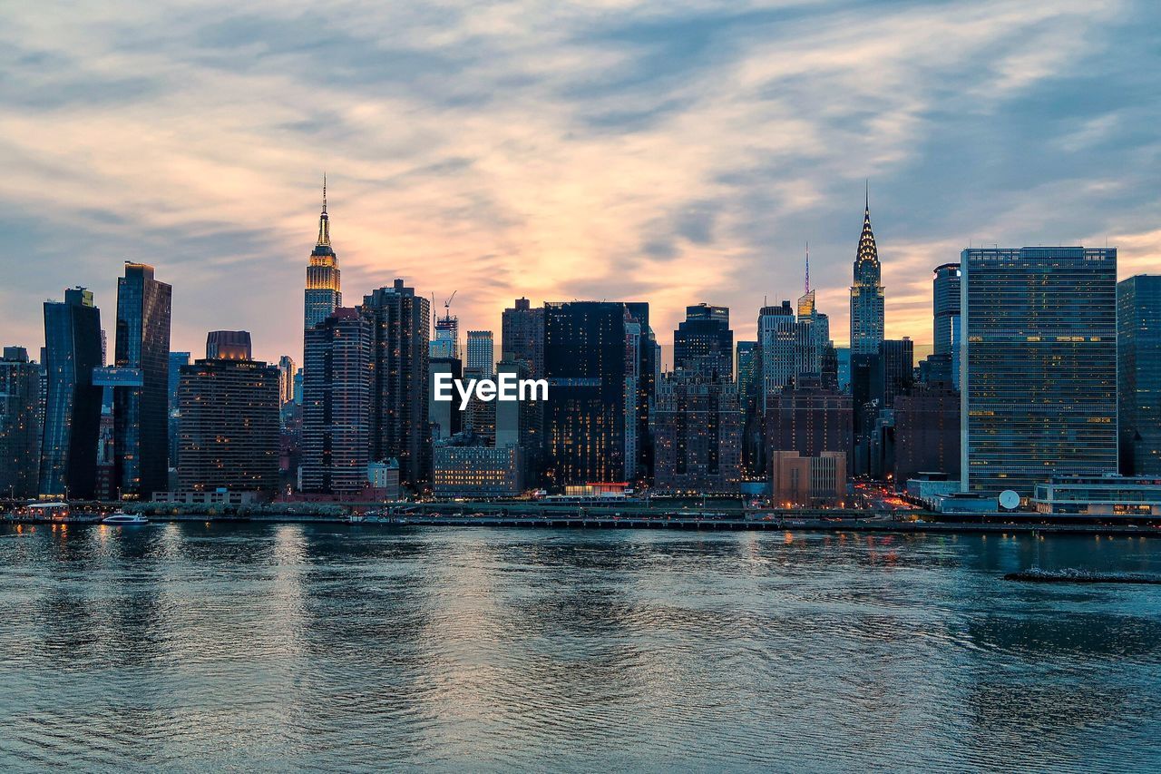 View of buildings at waterfront against cloudy sky