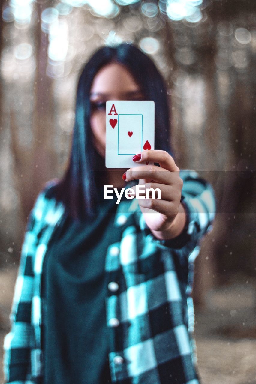 Portrait of woman covering face with card