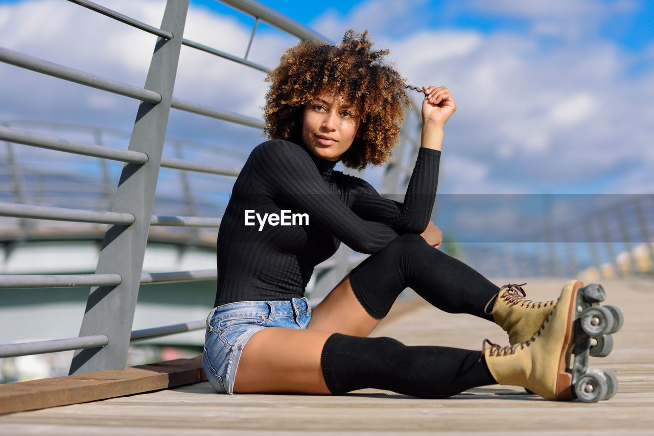 Thoughtful woman wearing roller skates while sitting on footbridge