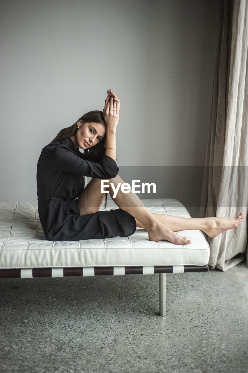 PORTRAIT OF WOMAN SITTING ON SOFA