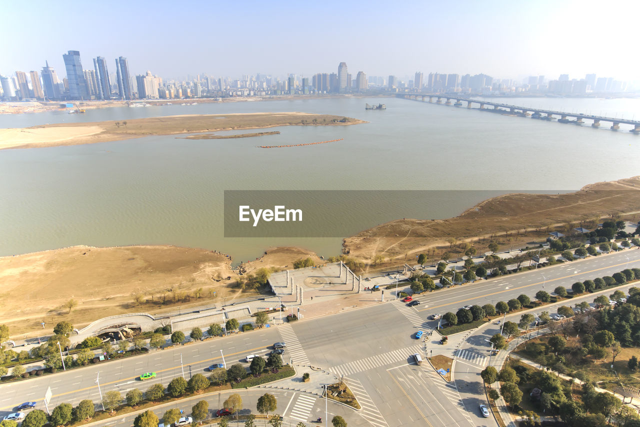 High angle view of road in city by river against sky