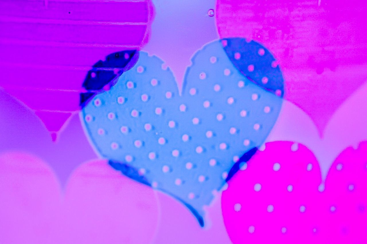 CLOSE-UP OF MULTI COLORED HEART SHAPE ON PINK FABRIC