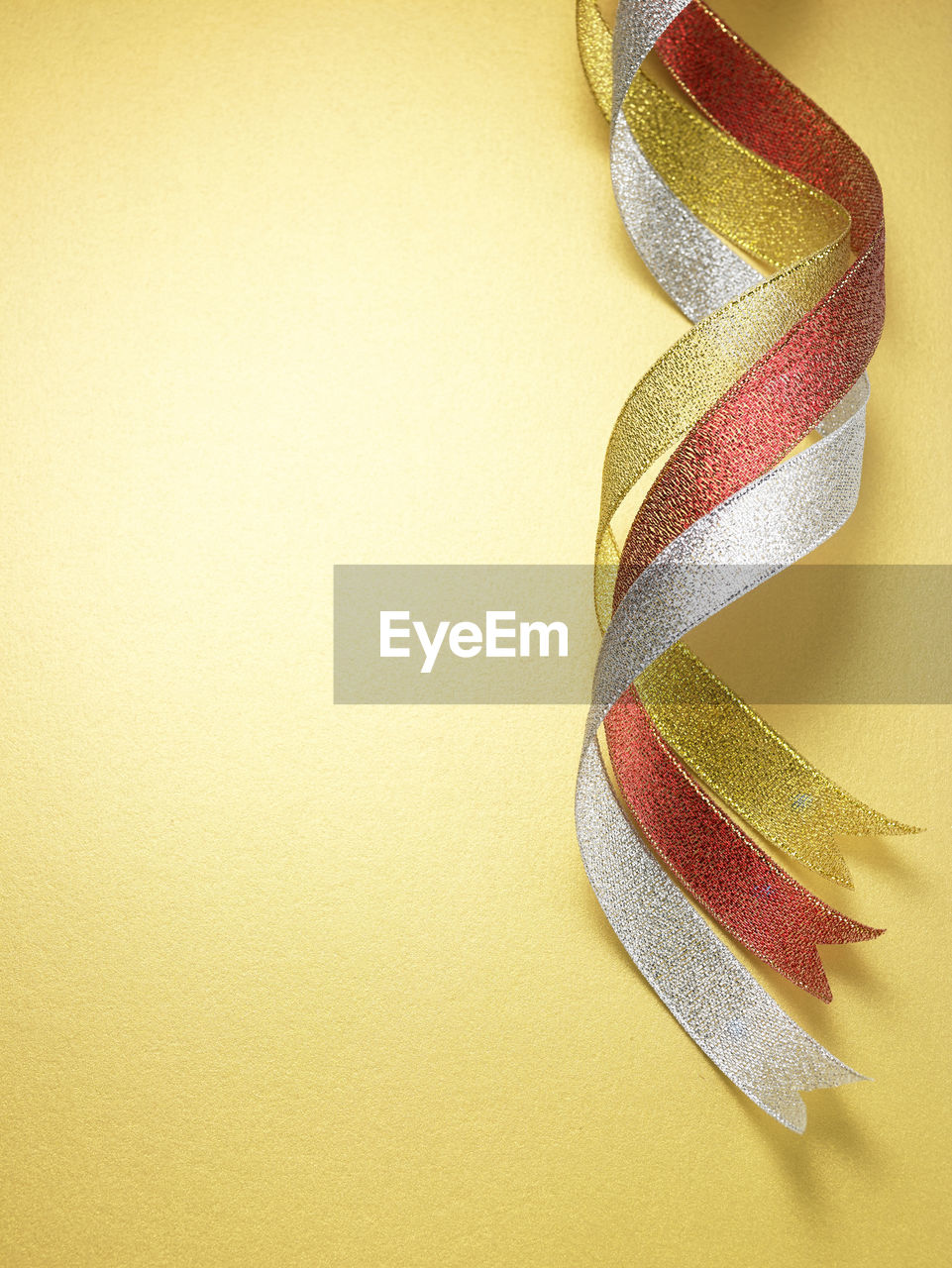 Close-up of multi colored ribbons over yellow background