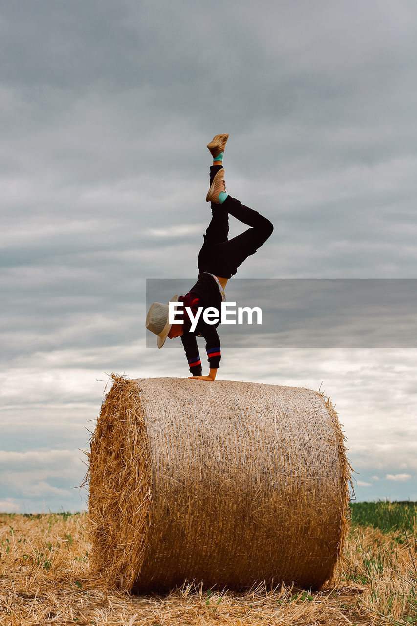 A child on a haystack does a handstand. carefree childhood in the country, summer mood