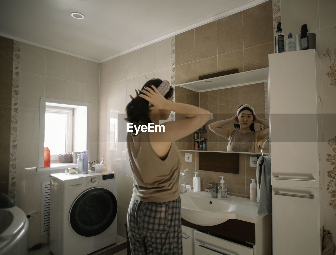 Asian beauty starts her morning routine with a reflection in the bathroom mirror