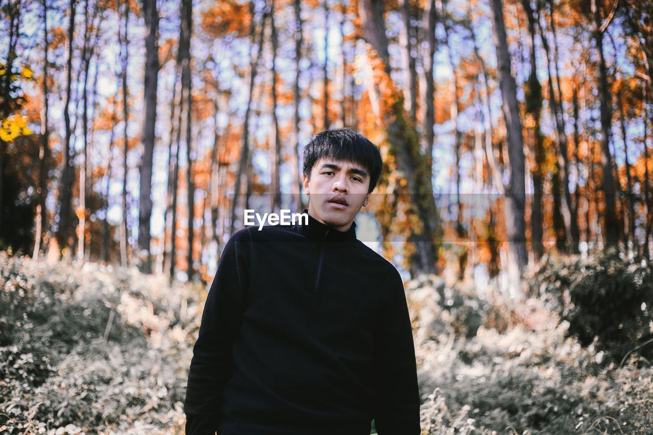 Portrait of young man standing in forest