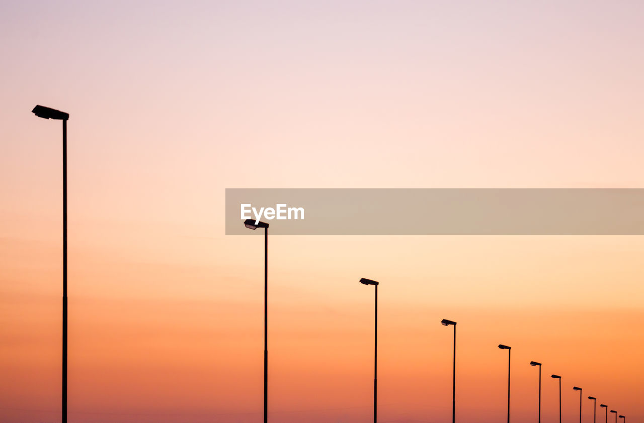 Low angle view of street lights against sky during sunset