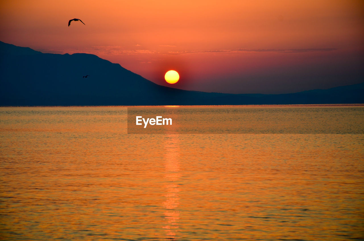 Scenic view of sea against orange sky