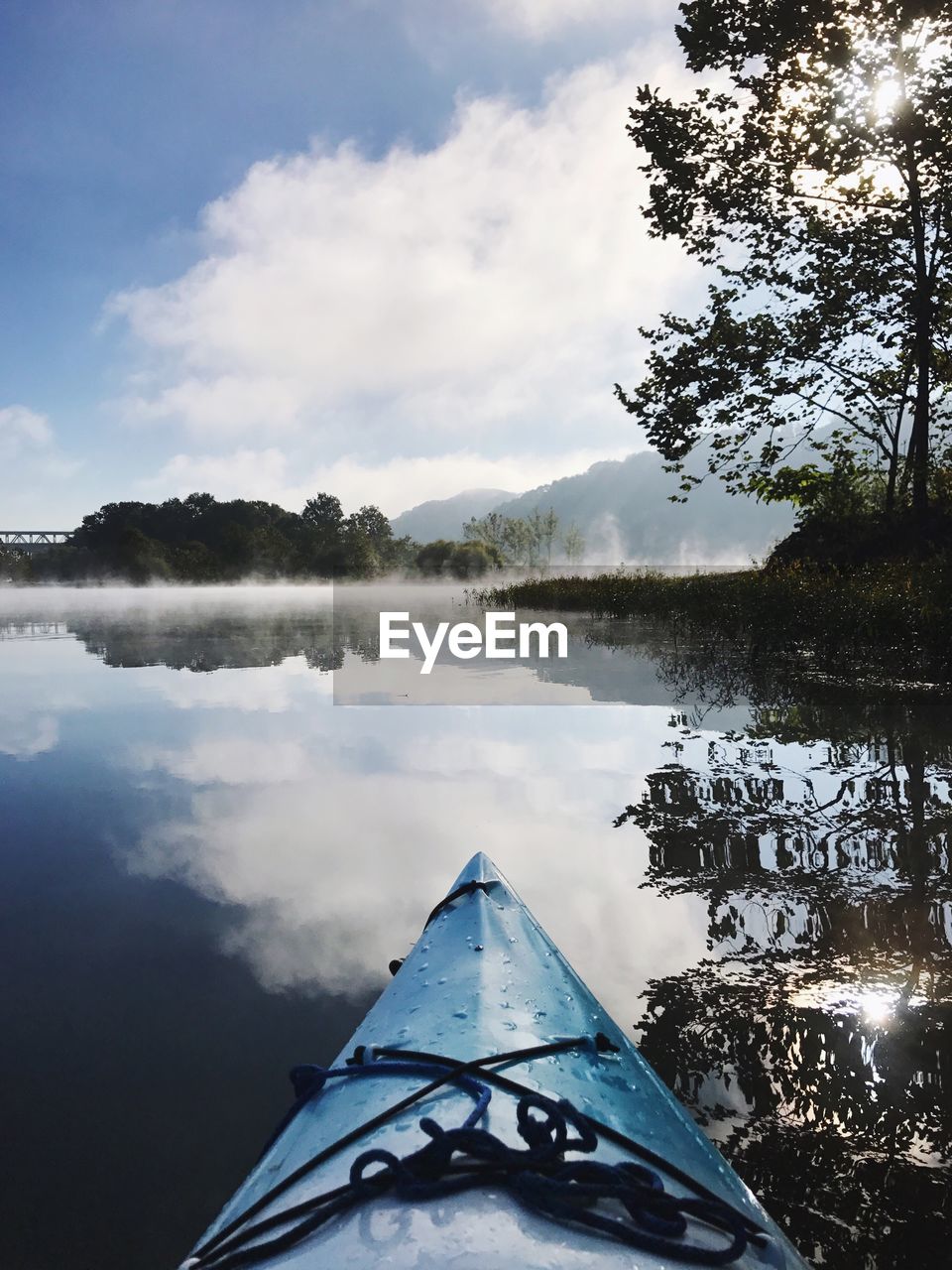 Cropped canoe by reflection of clouds in lake