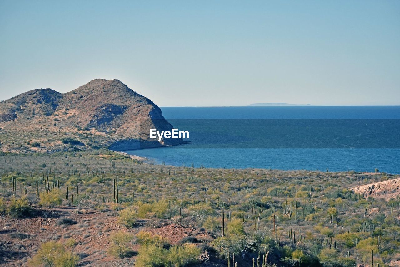 SCENIC VIEW OF SEA AND MOUNTAINS AGAINST CLEAR SKY