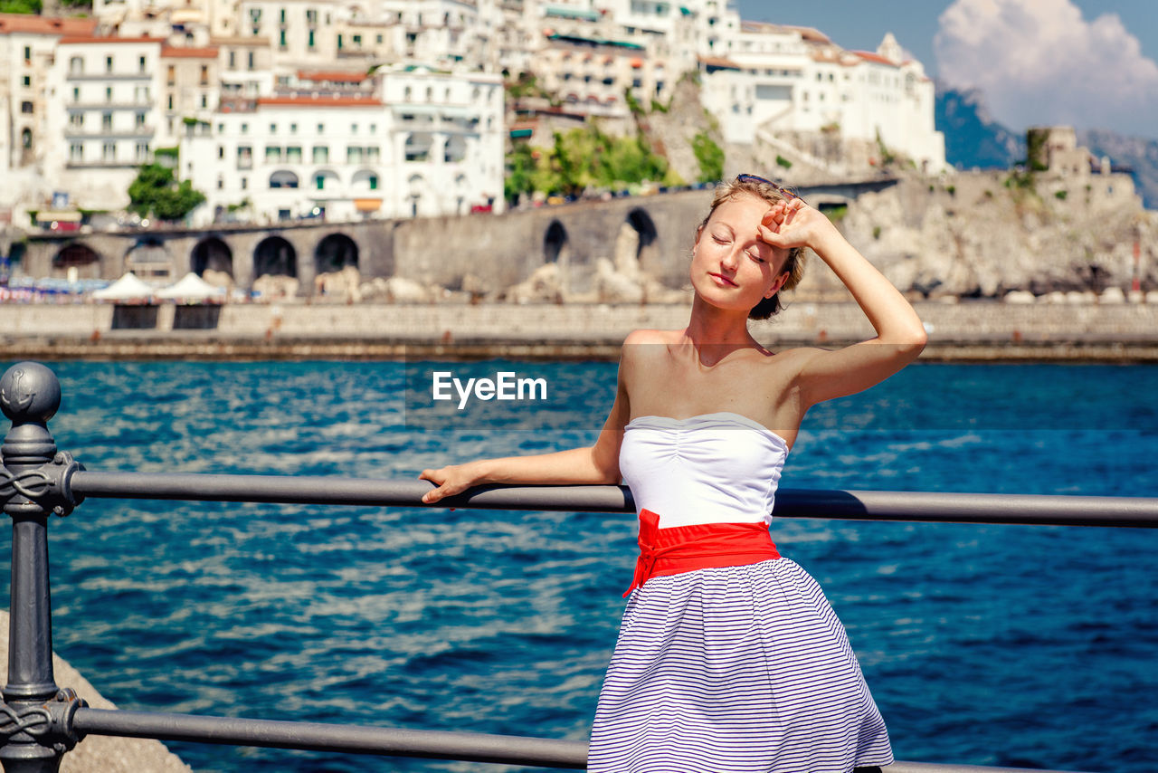 Woman standing by sea against atrani on sunny day