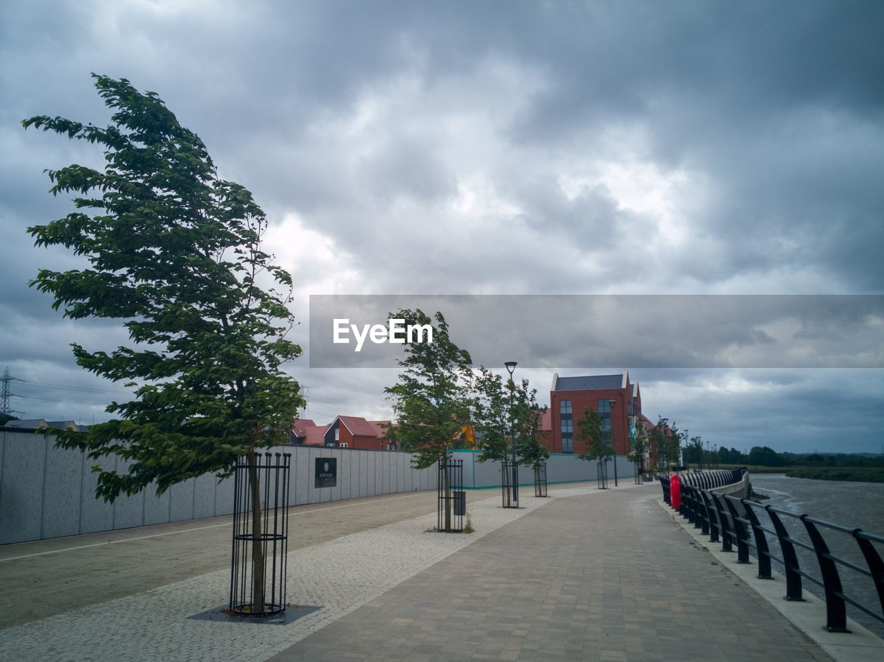 EMPTY FOOTPATH BY BUILDING AGAINST SKY