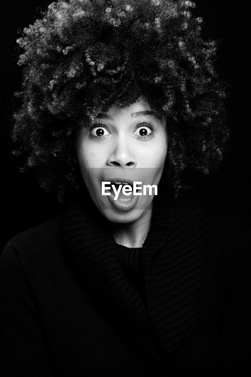 Close-up of afro teenage girl against black background