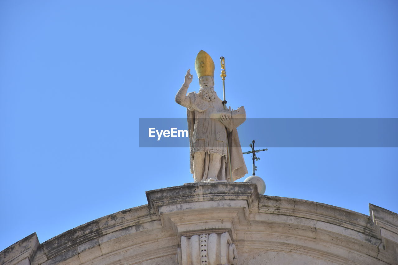 LOW ANGLE VIEW OF STATUES AGAINST BLUE SKY