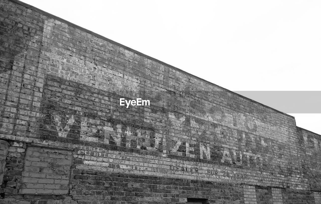 Low angle view of text on old building against clear sky