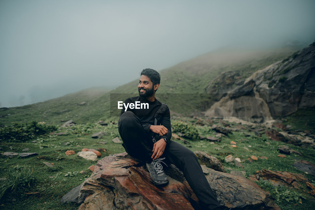 Young man standing on mountain against sky