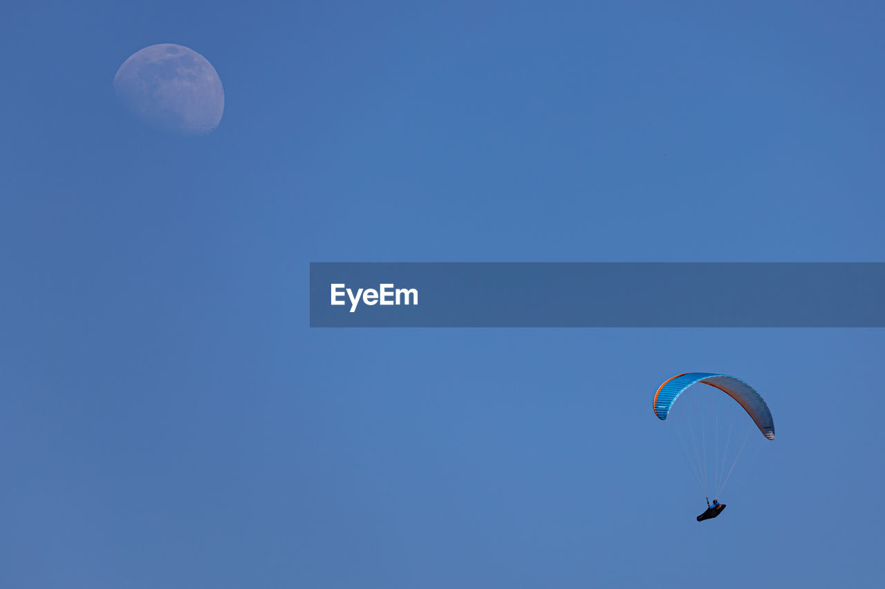 LOW ANGLE VIEW OF PARAGLIDING AGAINST BLUE SKY