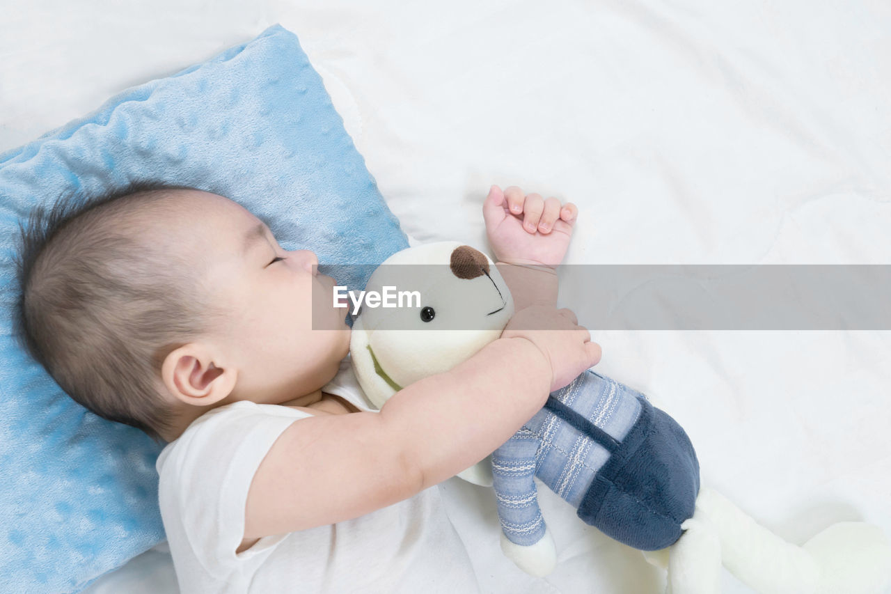 HIGH ANGLE VIEW OF BABY LYING ON BED