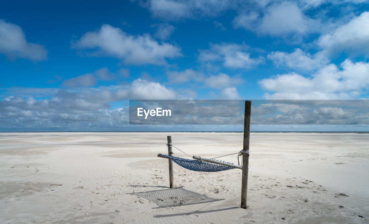 DECK CHAIRS ON BEACH AGAINST SKY