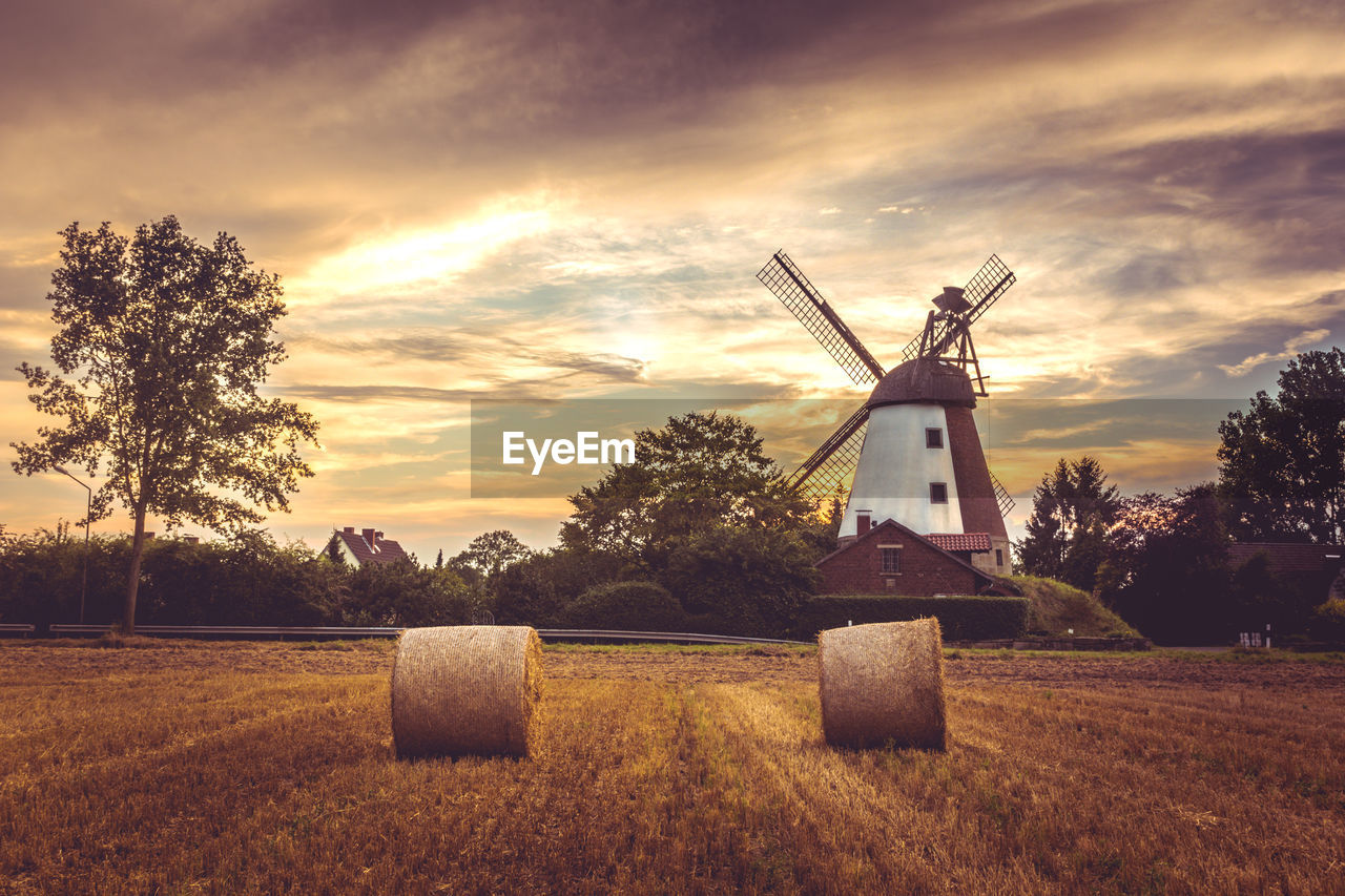 Traditional windmill on field against sky at sunset