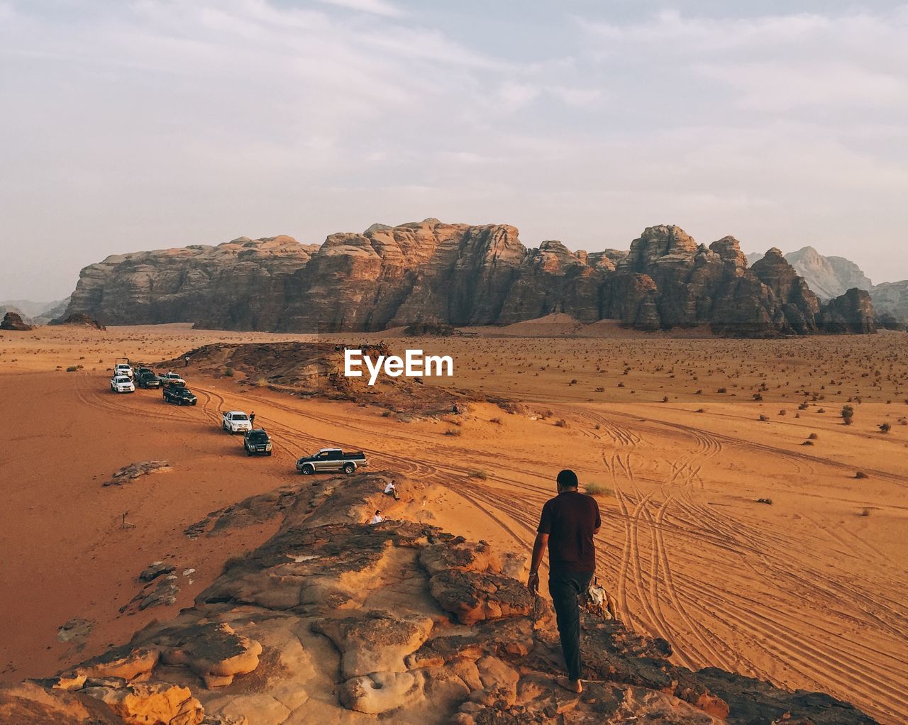 Rear view full length of man walking at desert against sky