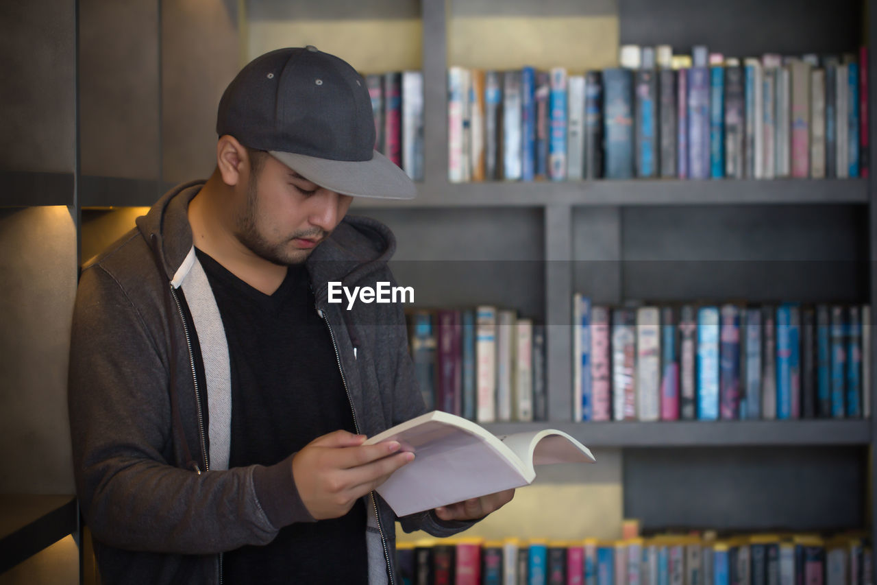 Young man reading book in library