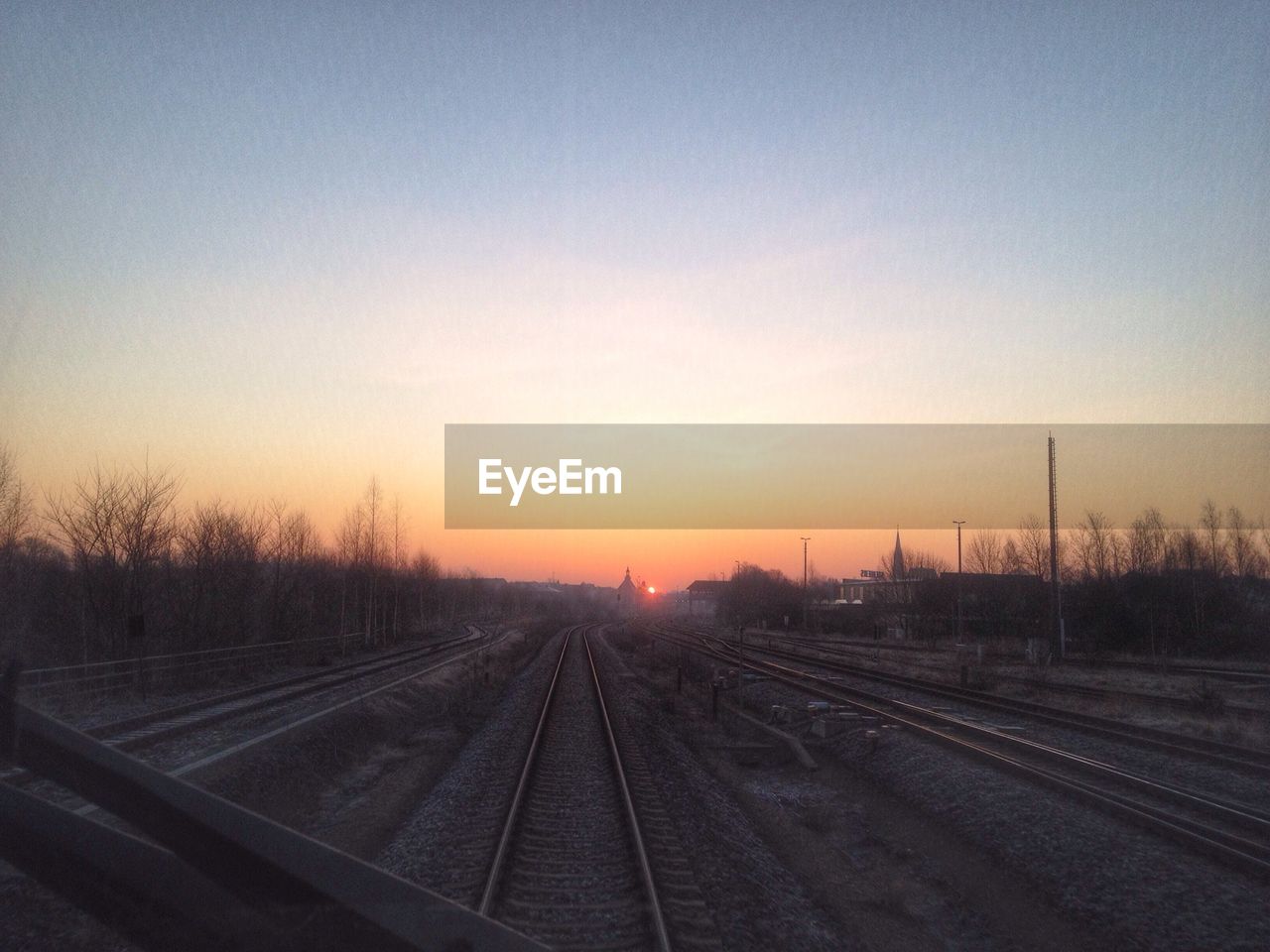 Railroad tracks against clear sky during sunset