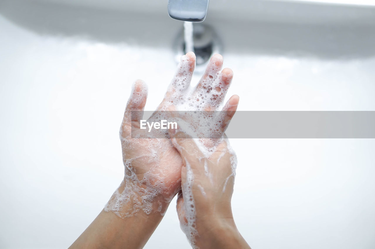 Cropped image of person washing hands in sink