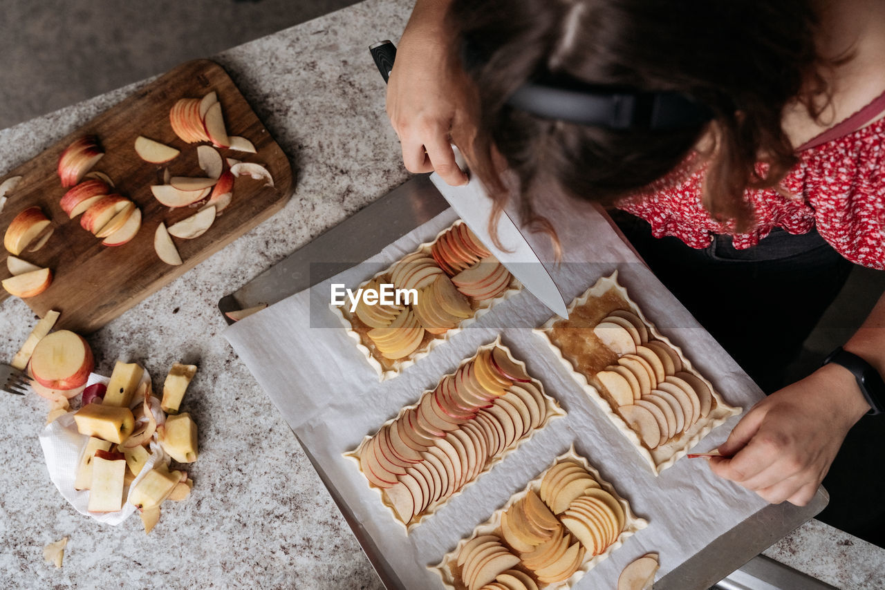 High-view angle of young adult women making pastry with apples