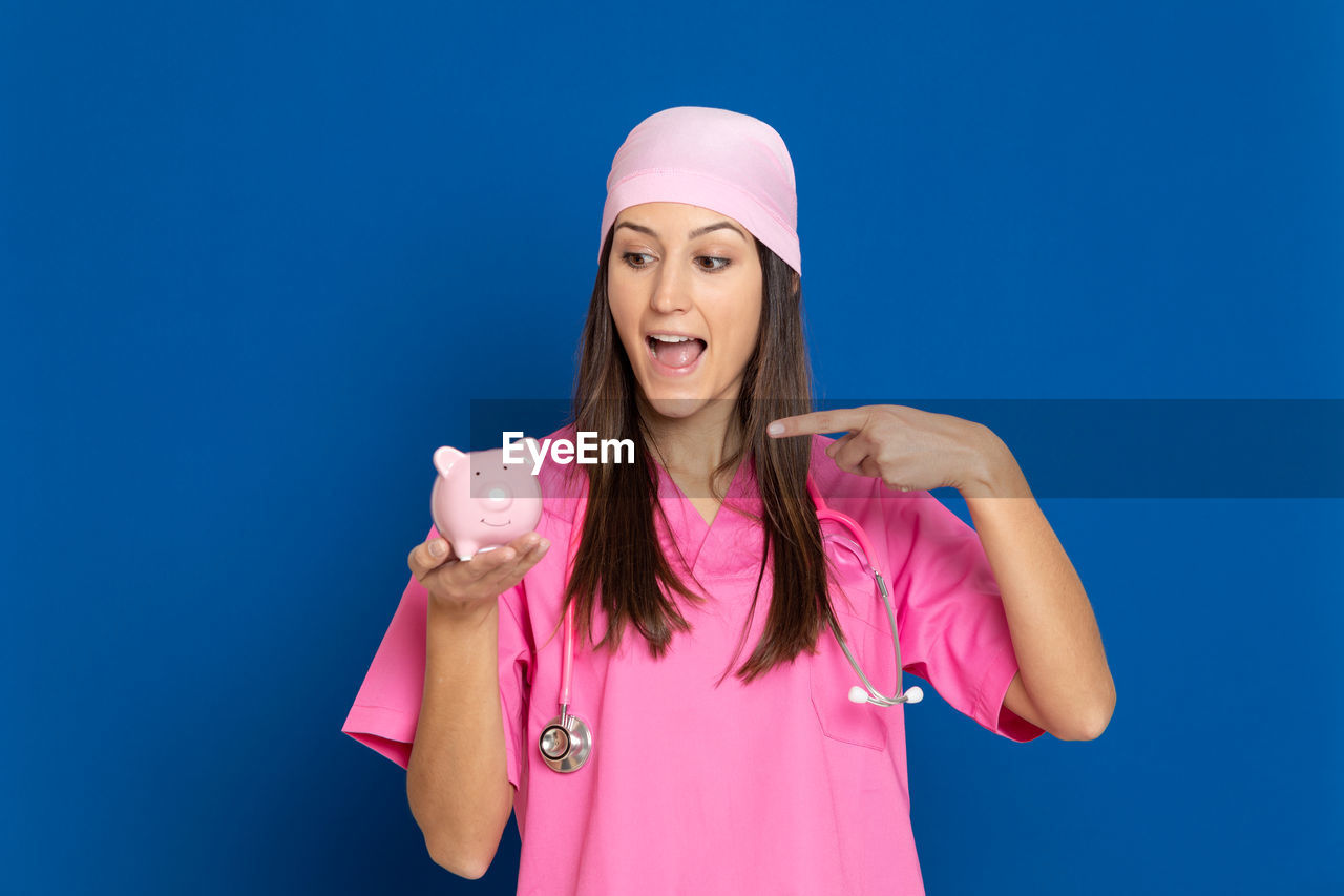 PORTRAIT OF YOUNG WOMAN STANDING AGAINST BLUE SKY