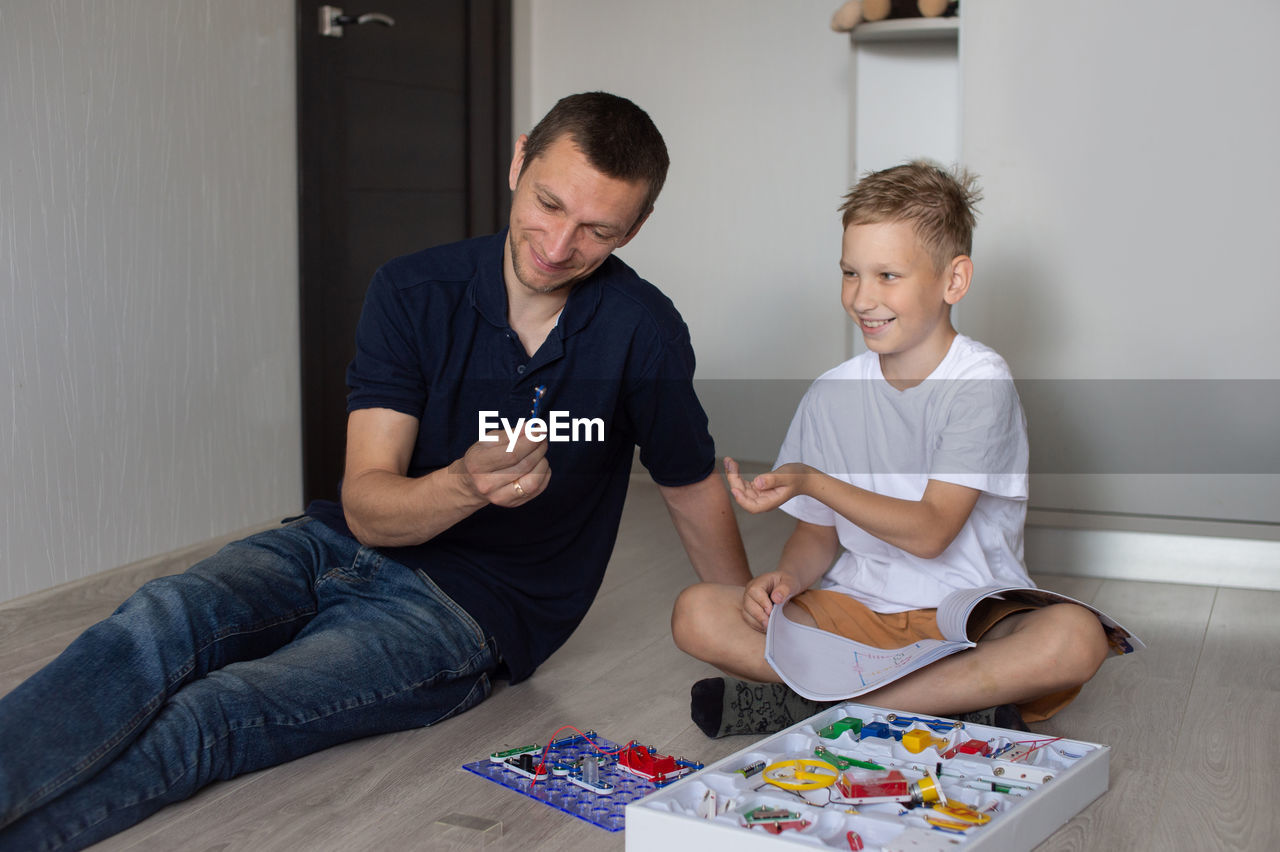 White t-shirt, electrical designer, lots of details, boy and man, dad and son, sit on the floor