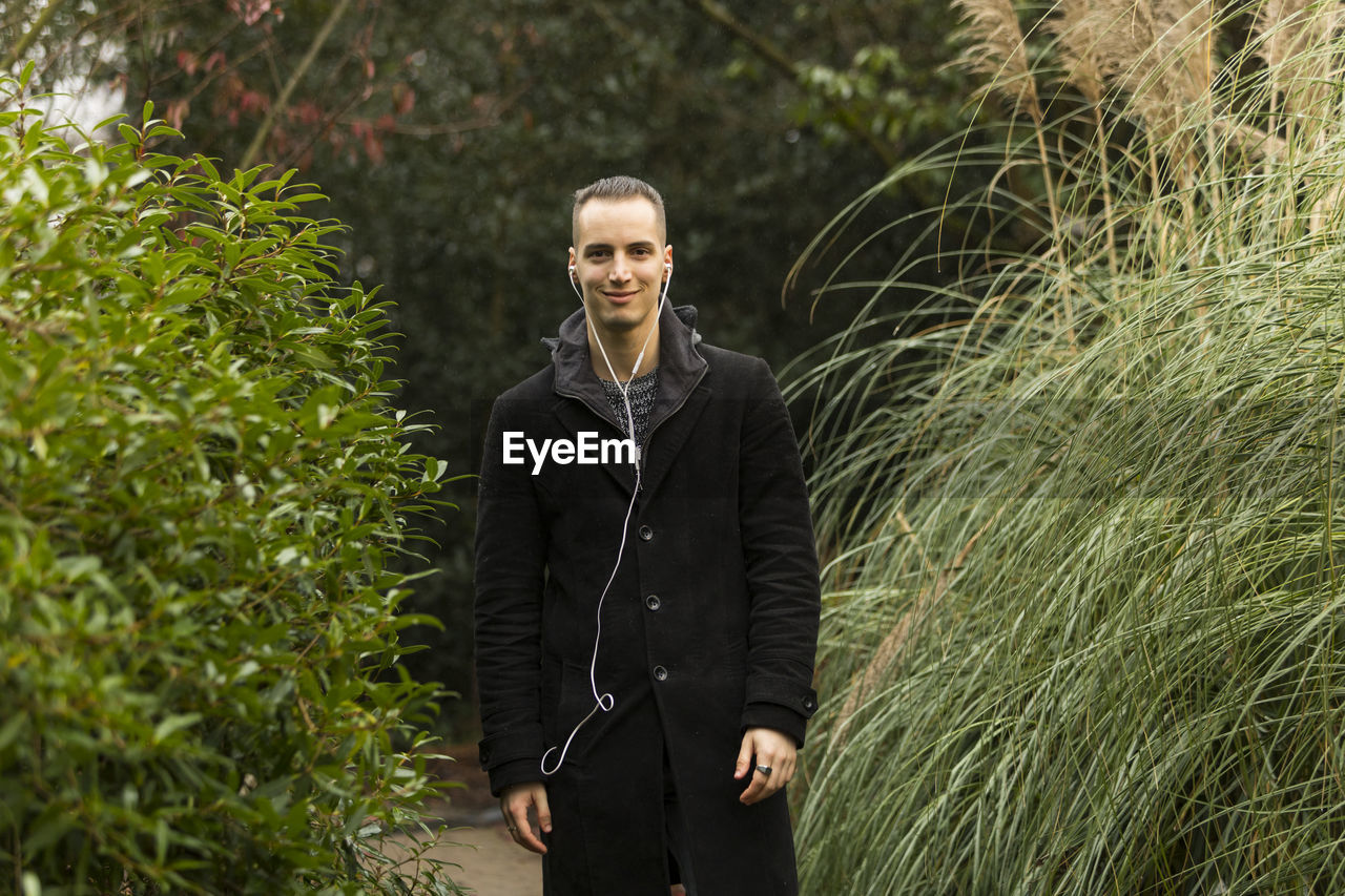 Portrait of young man standing against plants