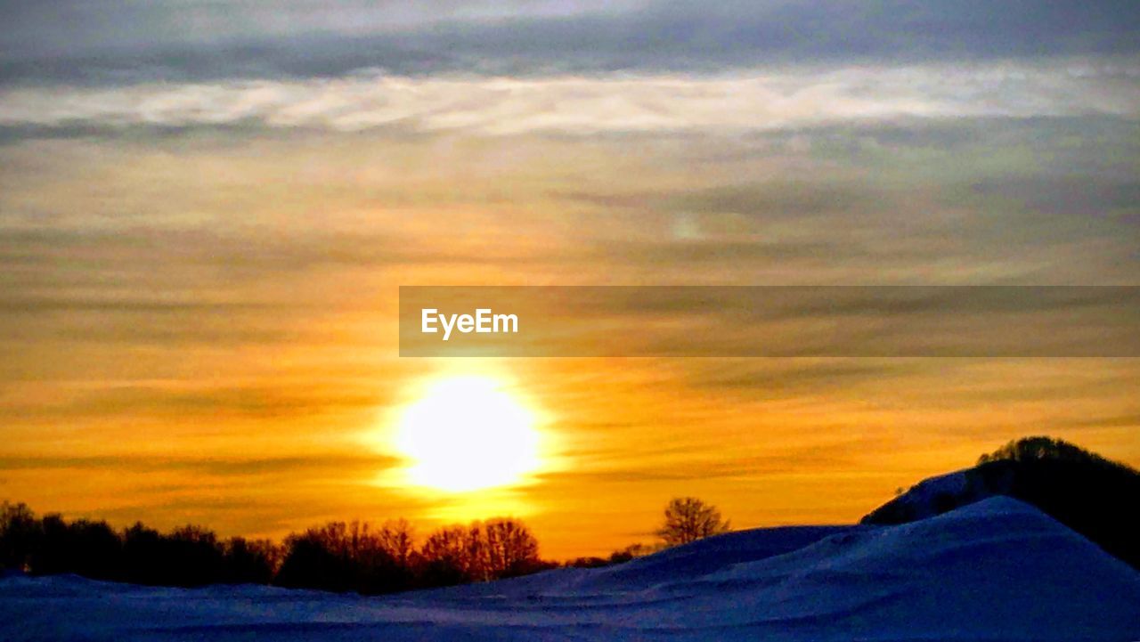 SNOW COVERED LANDSCAPE AGAINST ROMANTIC SKY AT SUNSET