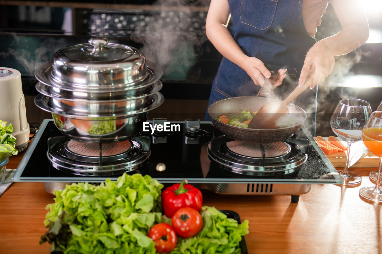 midsection of woman preparing food in container on table