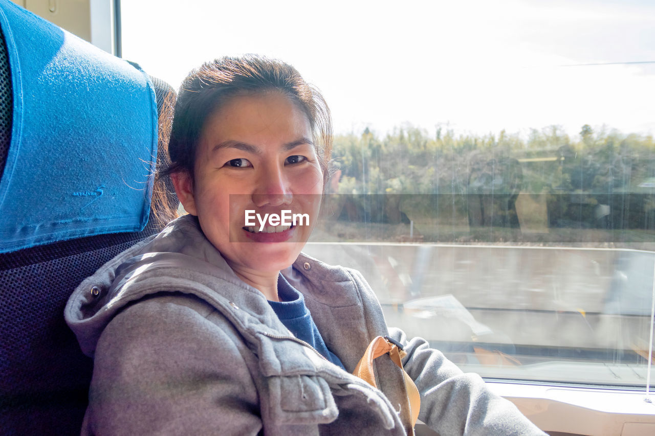 Portrait of smiling woman sitting in train by window